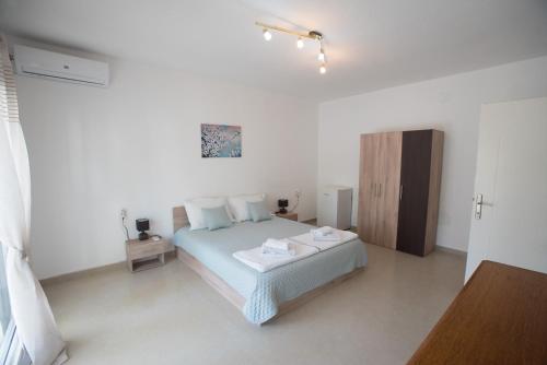 a white bedroom with a bed and a wooden cabinet at Three Palms in Gevgelija