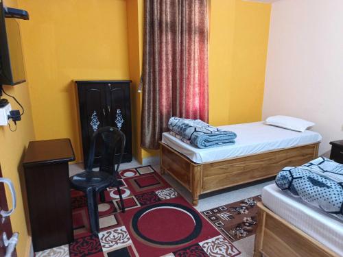 Habitación con 2 camas y una silla. en Ananya Homestay, en Patna
