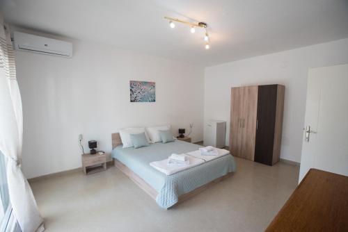 a white bedroom with a bed and a wooden cabinet at Three Palms in Gevgelija