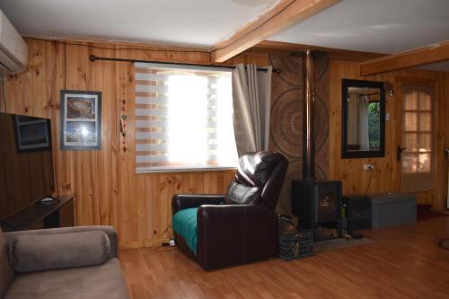 a living room with a leather chair and a window at casa bosque in Hornopiren