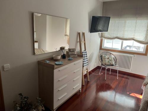 a bedroom with a dresser with a large mirror at Apartamento mirador de tambo in Combarro