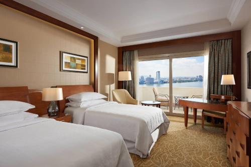 una camera d'albergo con 2 letti e una scrivania di Sheraton Cairo Hotel & Casino a Il Cairo