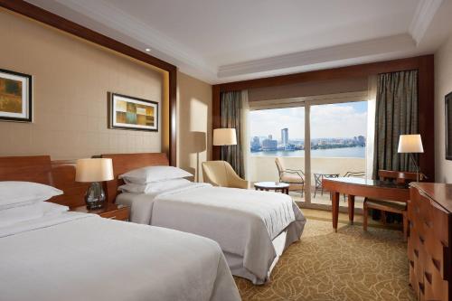 a hotel room with two beds and a desk at Sheraton Cairo Hotel & Casino in Cairo