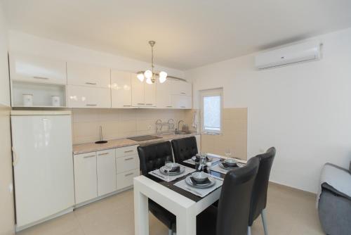 a kitchen with white cabinets and a table and chairs at Three Palms in Gevgelija
