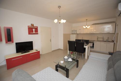 a living room with a couch and a tv and a kitchen at Three Palms in Gevgelija