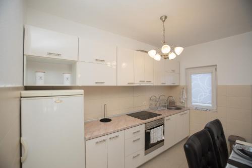 a kitchen with white cabinets and a white refrigerator at Three Palms in Gevgelija