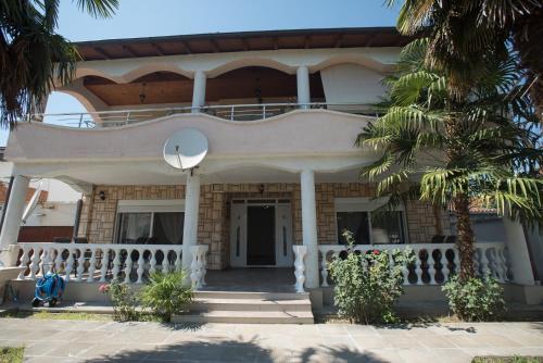 a white house with a balcony and palm trees at Three Palms in Gevgelija