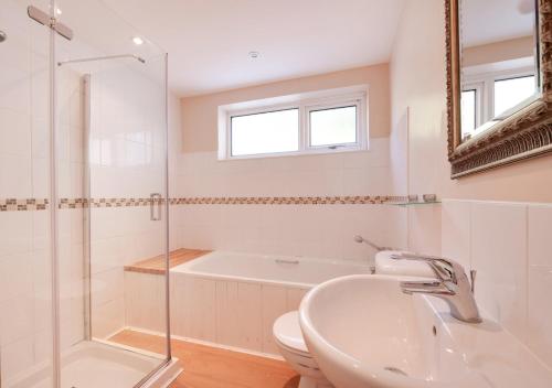 a bathroom with a tub and a sink and a toilet at Combe Way Cottage in Branscombe