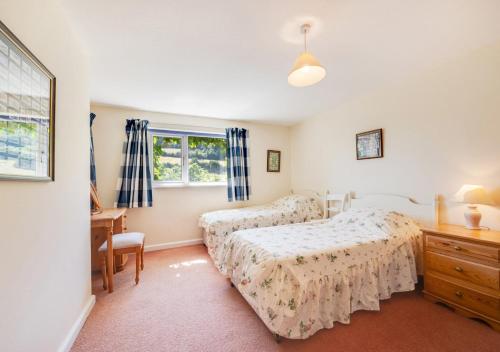 a bedroom with two beds and a desk and a window at Combe Way Cottage in Branscombe