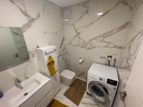 ein Badezimmer mit einem Waschbecken und einer Waschmaschine. in der Unterkunft Luxury Apartments in Balatonalmádi, Almádi Lux Apartman III - Pure Gold in Balatonalmádi