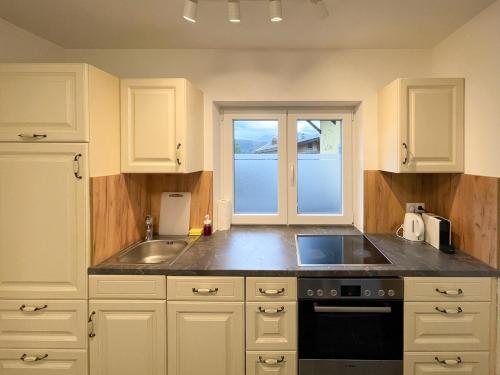 a kitchen with white cabinets and a sink and a window at Haus Sabine in Leutasch