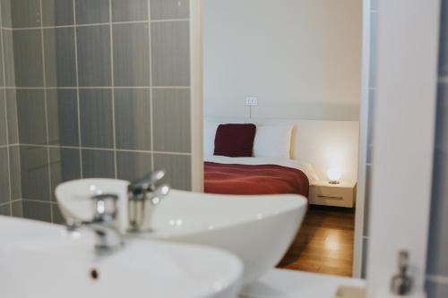 a bathroom with a sink and a bed and a mirror at Camelia's cozy place in Baia Mare