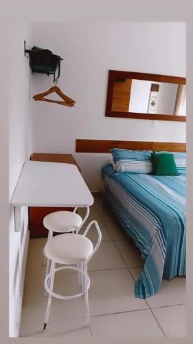 a small bedroom with a bed and a table and chairs at Pippo Suites Guarujá in Guarujá