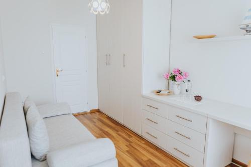 a white kitchen with a white counter and a chair at Camelia's cozy place in Baia Mare