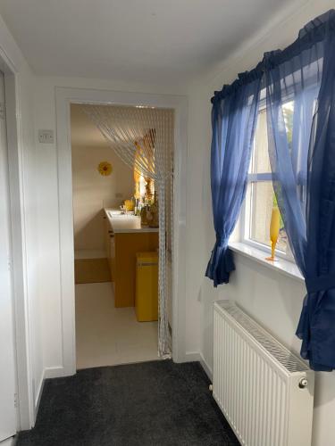 a bathroom with blue curtains and a sink and a window at The Steading with 7 Seater Hot Tub Aberdeenshire in Banff