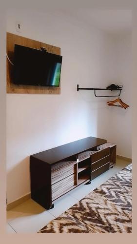 a living room with a tv on a wall at Pippo Suites Guarujá in Guarujá