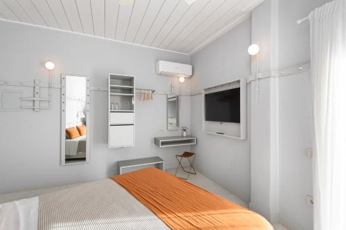 1 dormitorio con 1 cama y TV en la pared en Argonauta Hotel, en Parikia