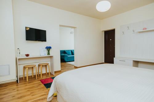 a white bedroom with a bed and a desk at Camelia's cozy place in Baia Mare