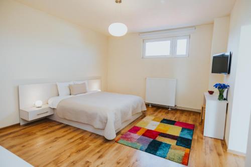 a bedroom with a white bed and a colorful rug at Camelia's cozy place in Baia Mare