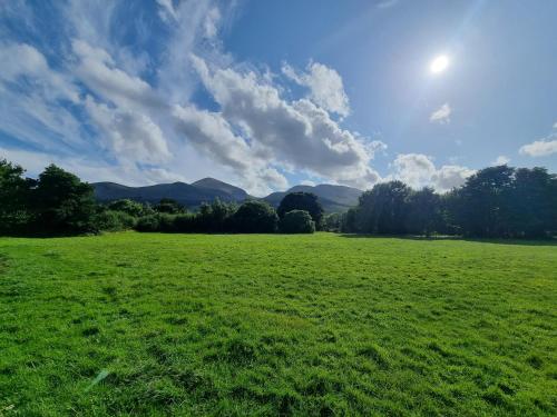 a field of green grass with mountains in the background at Donard View Apartment in Newcastle
