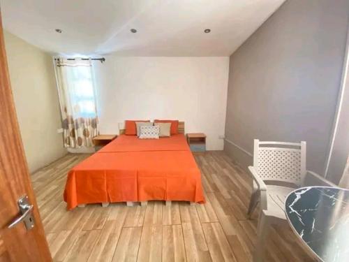 1 dormitorio con 1 cama con manta naranja en John family guesthouse service, en Roches Brunes