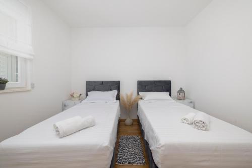 twee bedden in een kamer met witte muren bij LuSi Apartman Makarska in Makarska