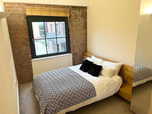 1 dormitorio con cama con almohadas y ventana en City Center 2 bedrooms Apartment, en Mánchester
