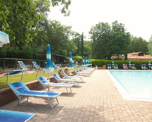 カステル・デル・ピアーノにある14 Holiday in Tuscany - Val d'Orcia - CASA PRIVATAのスイミングプールの横にパラソル付きのラウンジチェアが並ぶ