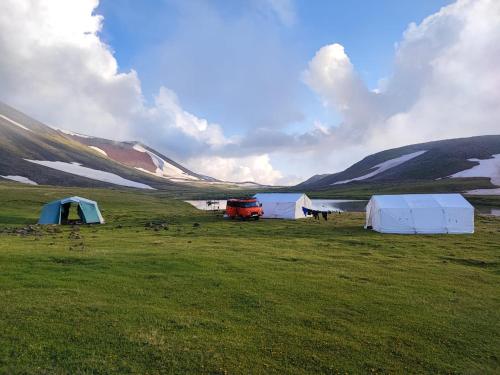 un grupo de tiendas de campaña en un campo junto a un lago en Highland Hostel, en Ereván