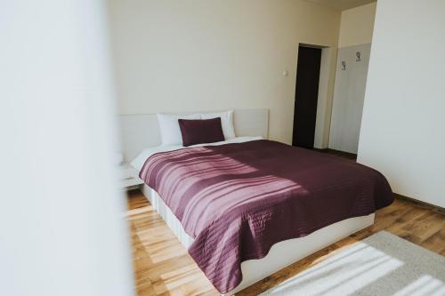 a bedroom with a bed with a purple blanket at Camelia's cozy place in Baia Mare