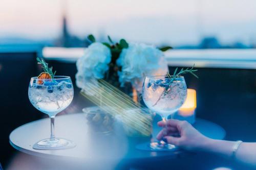 two wine glasses sitting on a table with a vase of flowers at The Ritz-Carlton, Vienna in Vienna