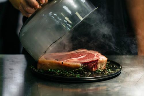 a person cooking a piece of meat on a grill at The Ritz-Carlton, Vienna in Vienna