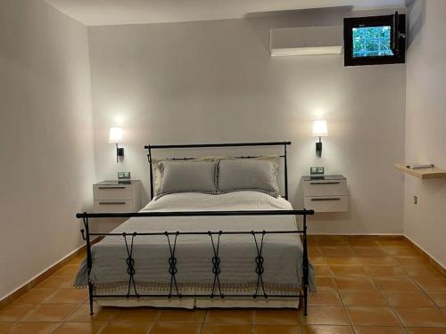 ein Schlafzimmer mit einem Bett mit zwei Nachttischen und zwei Lampen in der Unterkunft Volax280 Syros Amazing View in Episkopíon