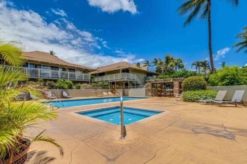 a house with a swimming pool and palm trees at Newly Renovated Studio on First Floor in Quiet Complex Across the Street from the Beach in Kihei