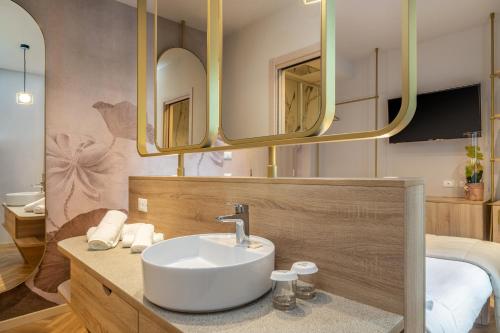a bathroom with a sink and two mirrors at Salus Smart & Chic Hotel in Lido di Jesolo