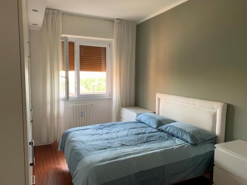 1 dormitorio con cama con sábanas azules y ventana en Appartamento incantevole a San Donato Milanese, en San Donato Milanese
