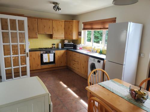 a kitchen with wooden cabinets and a white refrigerator at Bluebell House in Newry
