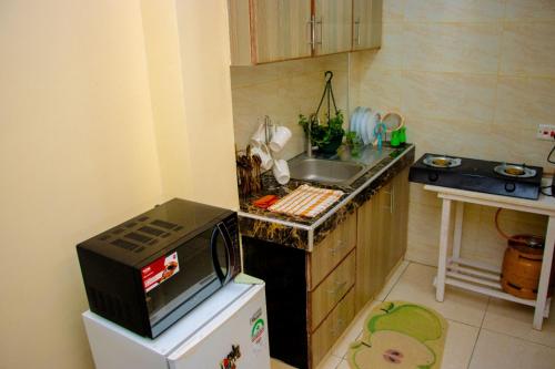 a small kitchen with a microwave on top of a refrigerator at Kayas' Home away from Home! in Kilifi
