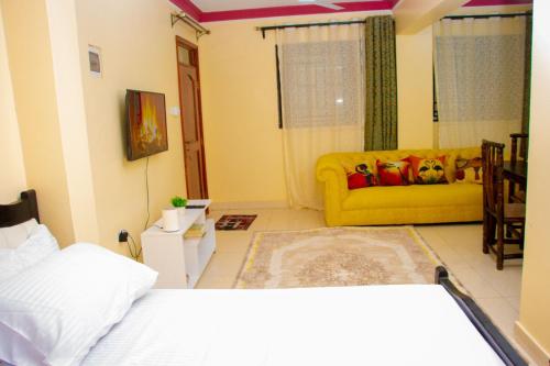 a bedroom with a bed and a yellow couch at Kayas' Home away from Home! in Kilifi