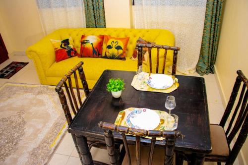 a table and chairs with a yellow couch in a living room at Kayas' Home away from Home! in Kilifi