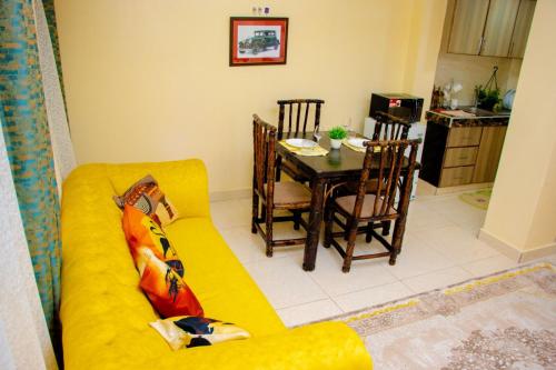 a living room with a yellow couch and a table at Kayas' Home away from Home! in Kilifi