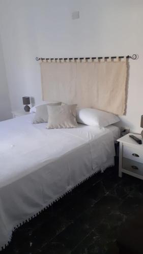 a bedroom with a large white bed and a night stand at Orgosio in Santa Maria Navarrese