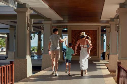 una famiglia che cammina lungo il corridoio di una casa di Phuket Marriott Resort and Spa, Nai Yang Beach a Nai Yang Beach