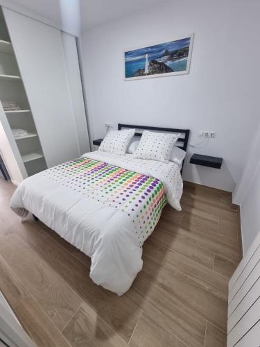 a white bedroom with a bed with a colorful blanket at Apartamento Regina in Santiago de Compostela