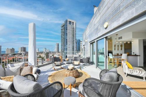 a balcony with chairs and furniture on a building at The Radiant By HolyGuest in Tel Aviv