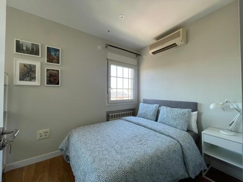 sypialnia z łóżkiem z niebieską kołdrą i oknem w obiekcie Rooms Pilarica w Madrycie