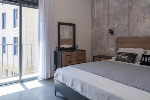 1 dormitorio con cama, espejo y ventana en ARISTO luxury suites Jerusalem city center, en Jerusalén