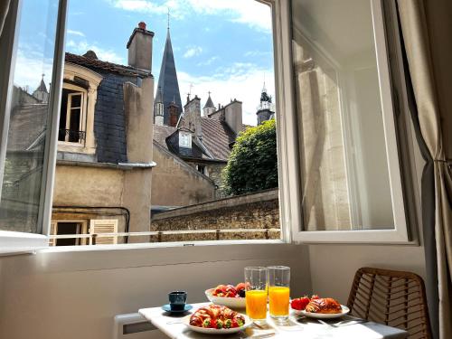 une table avec deux assiettes de nourriture et de boissons et une fenêtre dans l'établissement La Comtesse - Our Lady Church View - Heart of Dijon, à Dijon
