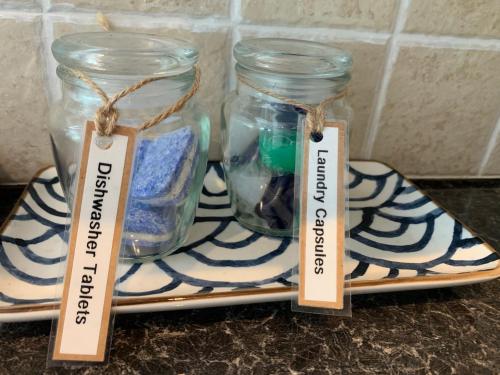 two glass jars on a plate with tags on them at The Apartment, Bridge House in Laxey