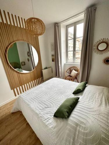 1 dormitorio con cama con almohadas verdes y espejo en Appartement Cosy Place Delille, en Clermont-Ferrand